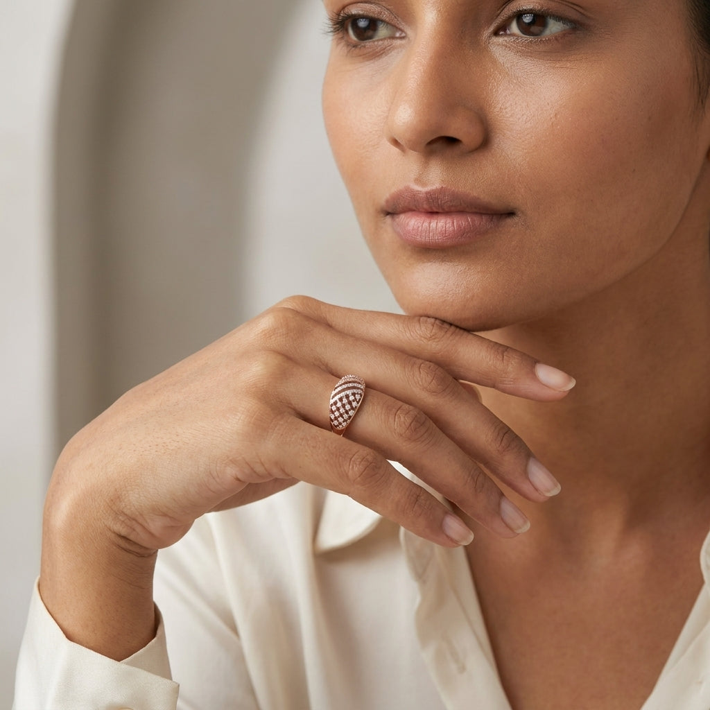 A close-up lifestyle shot of a woman wearing a gold-toned ring with a curved, openwork design on her finger, wearing a cream-colored blouse.