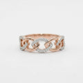 A close-up of a delicate rose gold ring with small clear stones, set against a plain light background.