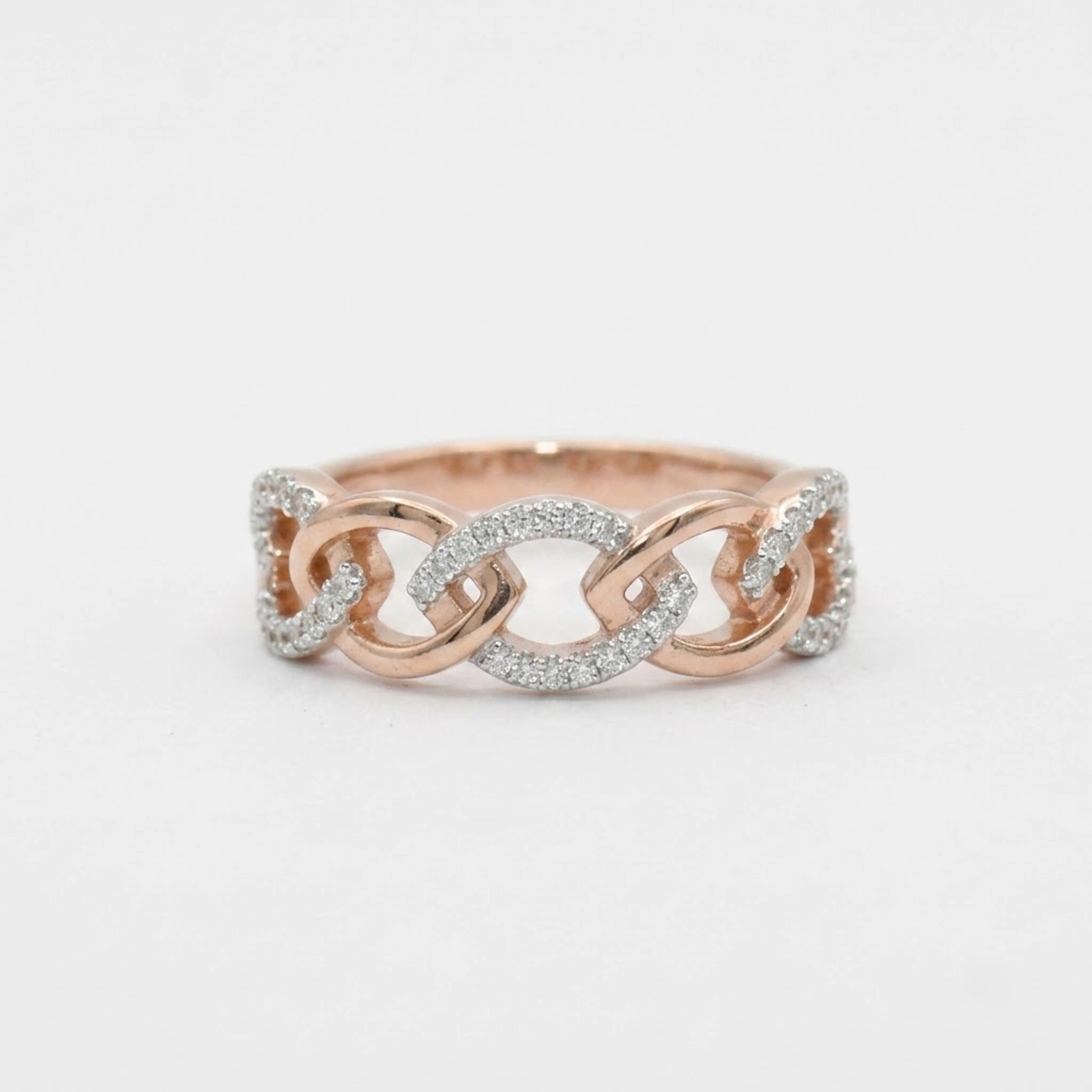 A close-up of a delicate rose gold ring with small clear stones, set against a plain light background.