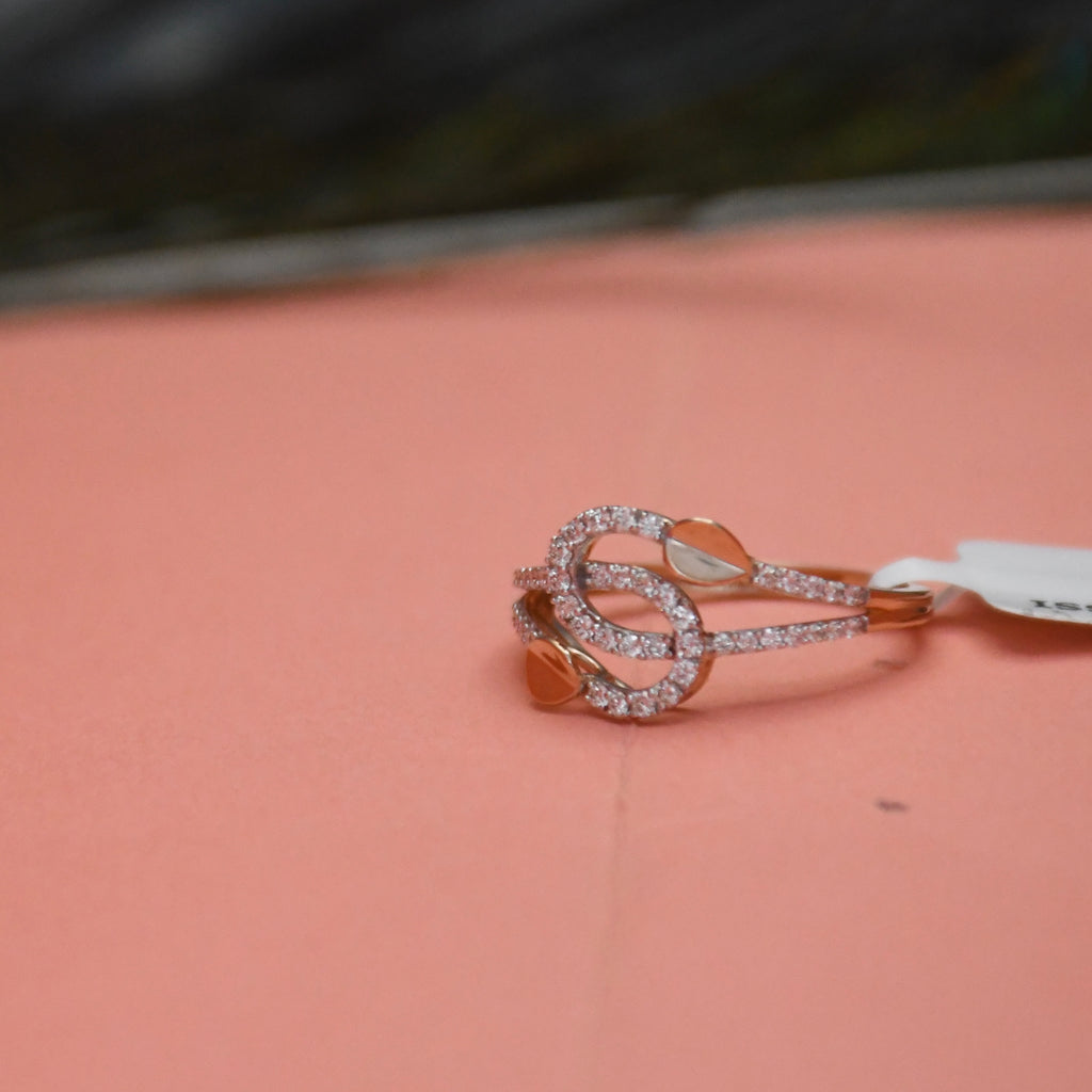A rose gold ring with a double knot design, embellished with pavé diamonds, resting on a dusty pink surface.