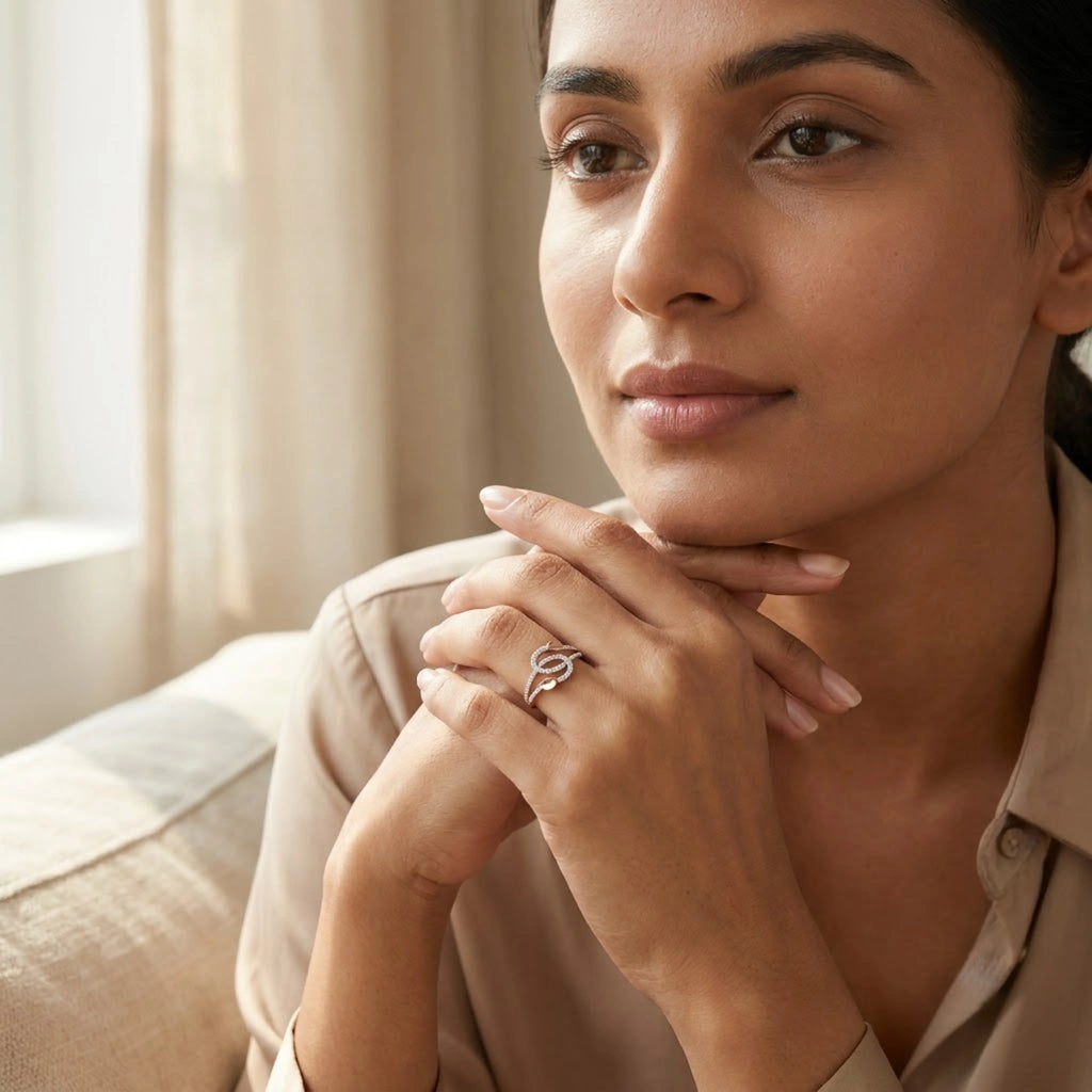 A woman wearing a diamond ring with a shaped design, posing in a warm, softly lit indoor setting.