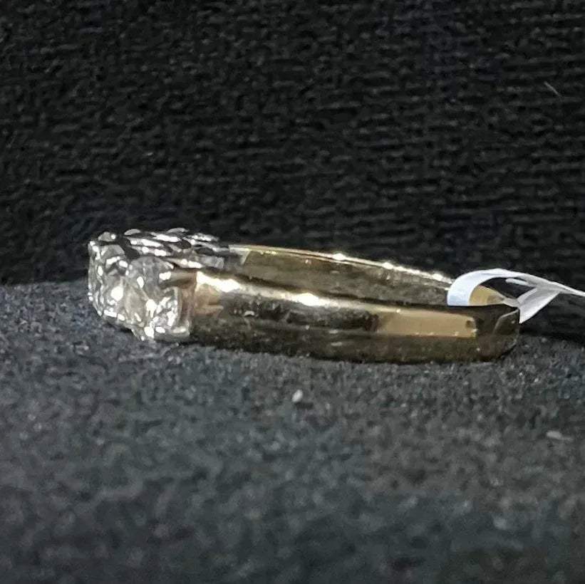 A close-up image of a white gold half eternity ring featuring a row of round brilliant-cut diamonds set in prongs, displayed on a black rough surface against a dark background, highlighting the sparkle and detailed craftsmanship of the ring.
