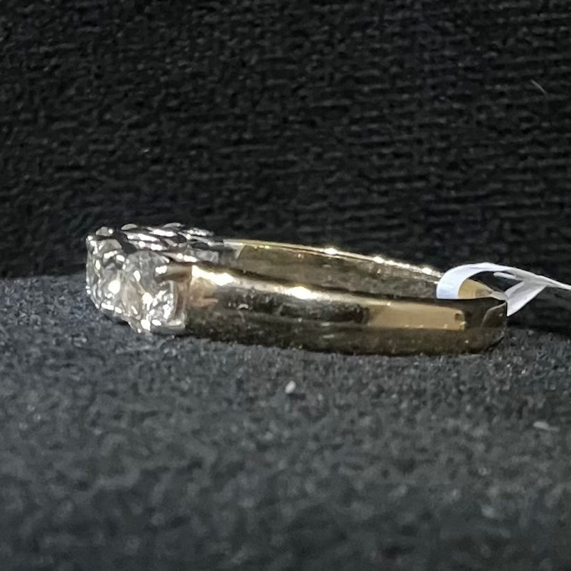 A close-up image of a white gold half eternity ring featuring a row of round brilliant-cut diamonds set in prongs, displayed on a black rough surface against a dark background, highlighting the sparkle and detailed craftsmanship of the ring.