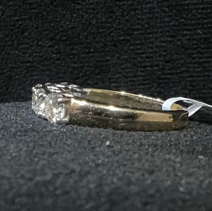 A close-up image of a white gold half eternity ring featuring a row of round brilliant-cut diamonds set in prongs, displayed on a black rough surface against a dark background, highlighting the sparkle and detailed craftsmanship of the ring.