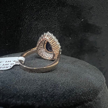 A gold band ring with a sparkling blue color stone and clear diamond set in a brilliant cut, displayed on a black mannequin bust.