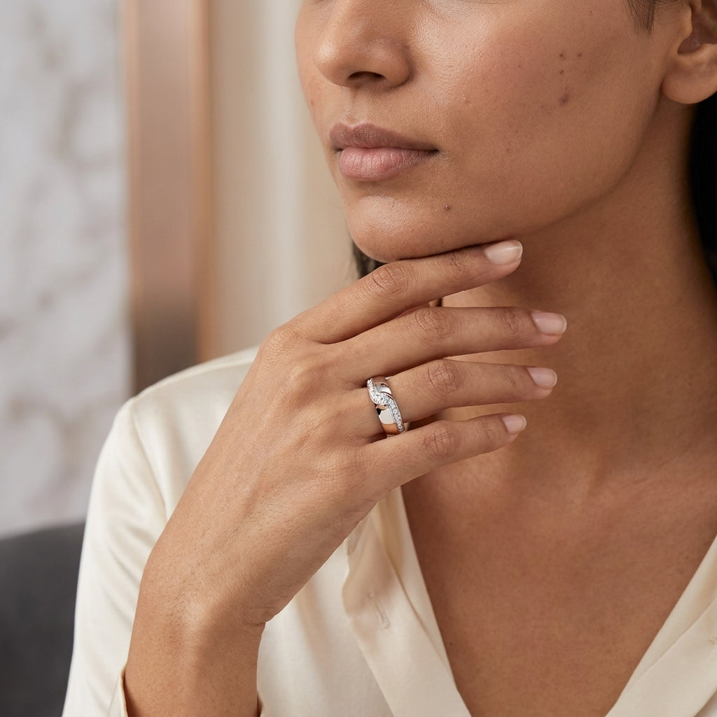 A gold diamond ring with a combination of white and rose gold, featuring a solitaire diamond on the top center and side diamonds along the band is worn in a woman's finger.