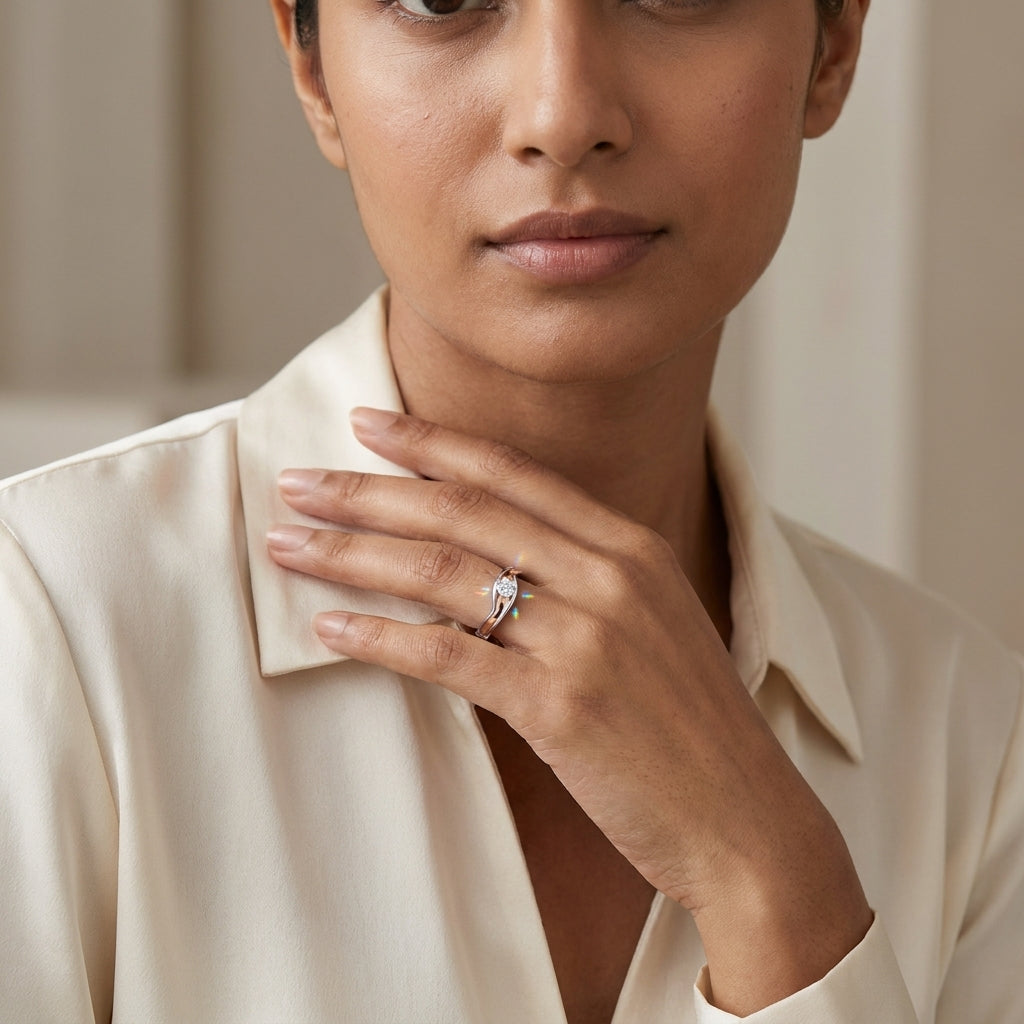 A solitaire diamond ring with a gold band featuring a single diamond at the center, set in a white gold or white gold band with a rose gold accent on the middle worn in a woman's finger against a neutral background.