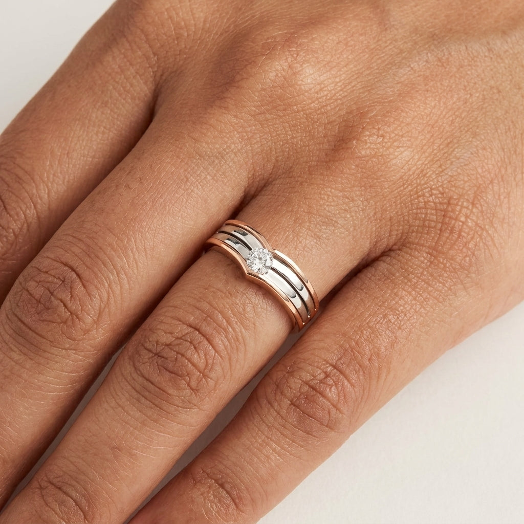 Two-tone gold ring with solitaire diamond worn in a hand's finger.