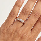 A solitaire diamond ring with a combination of white and rose gold, featuring a central diamond surrounded by smaller side diamonds on the band is worn in a hand's finger.