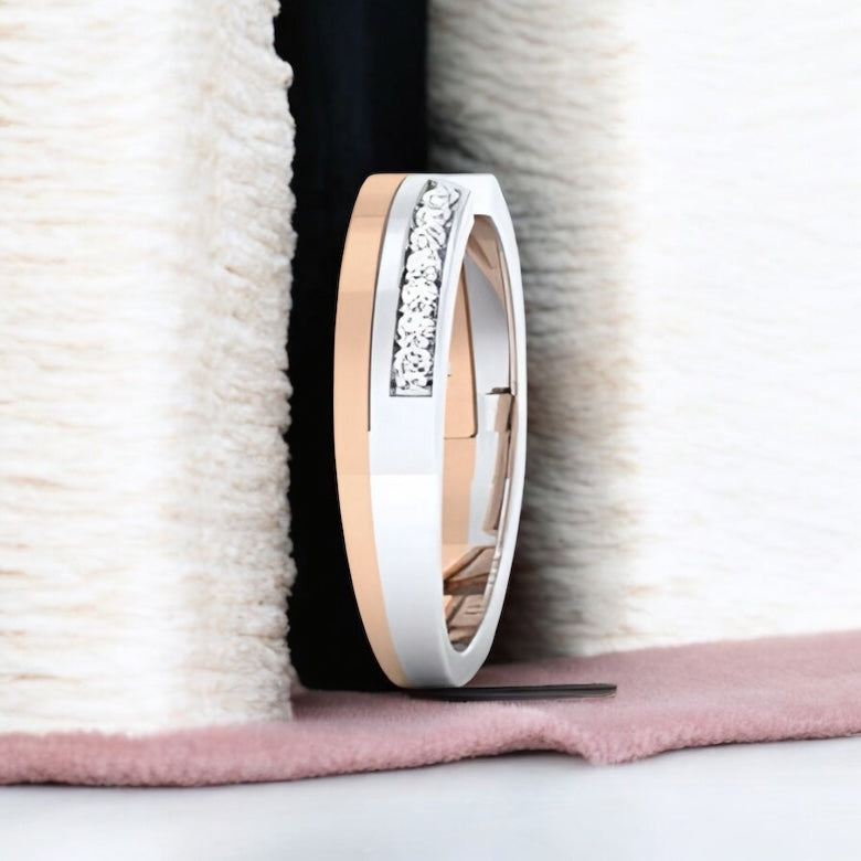Two rose gold and white gold bands with diamond accents on a textured surface.