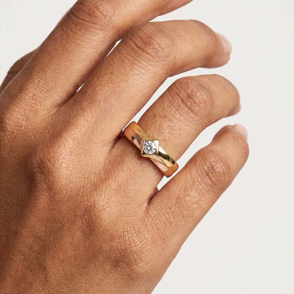 Close-up of a two-tone gold ring with a diamond worn in a hand's finger