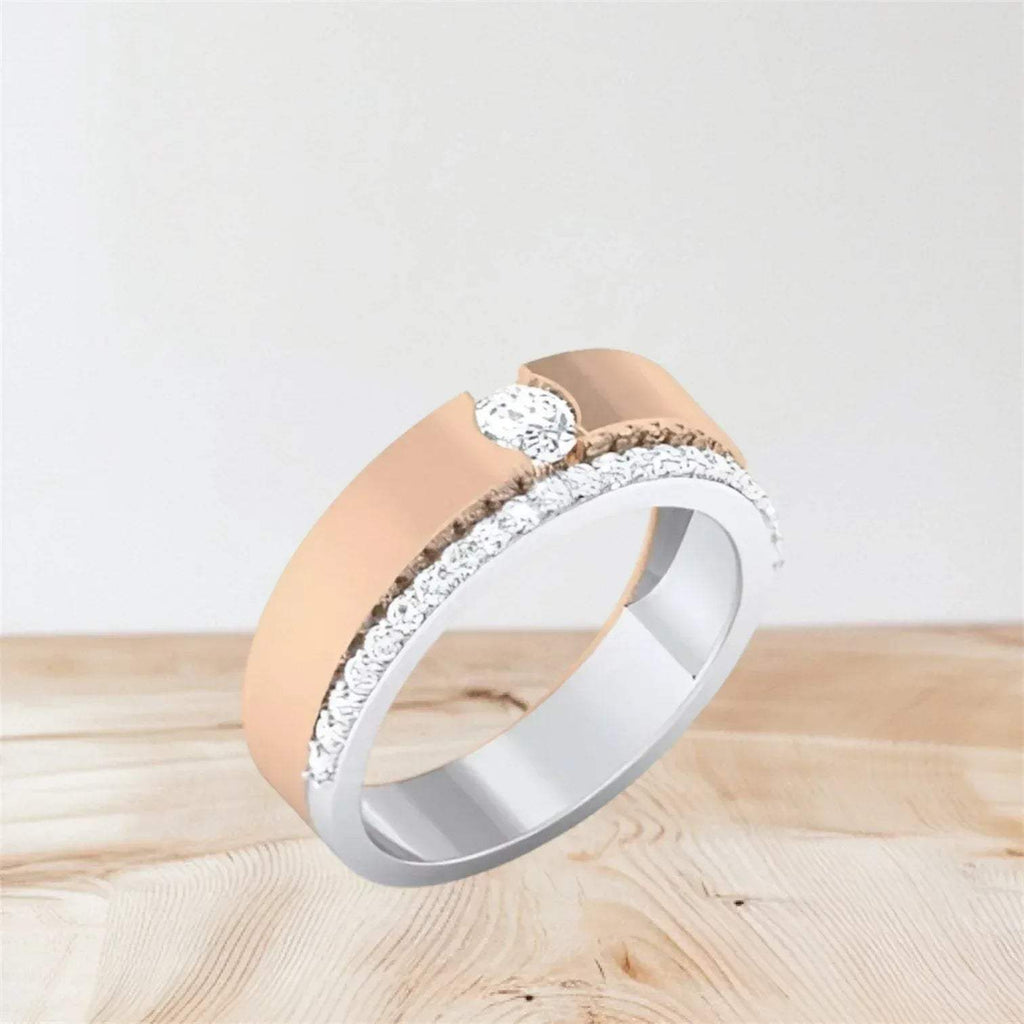 Two-tone diamond ring with rose gold and white gold bands on a light wooden surface.