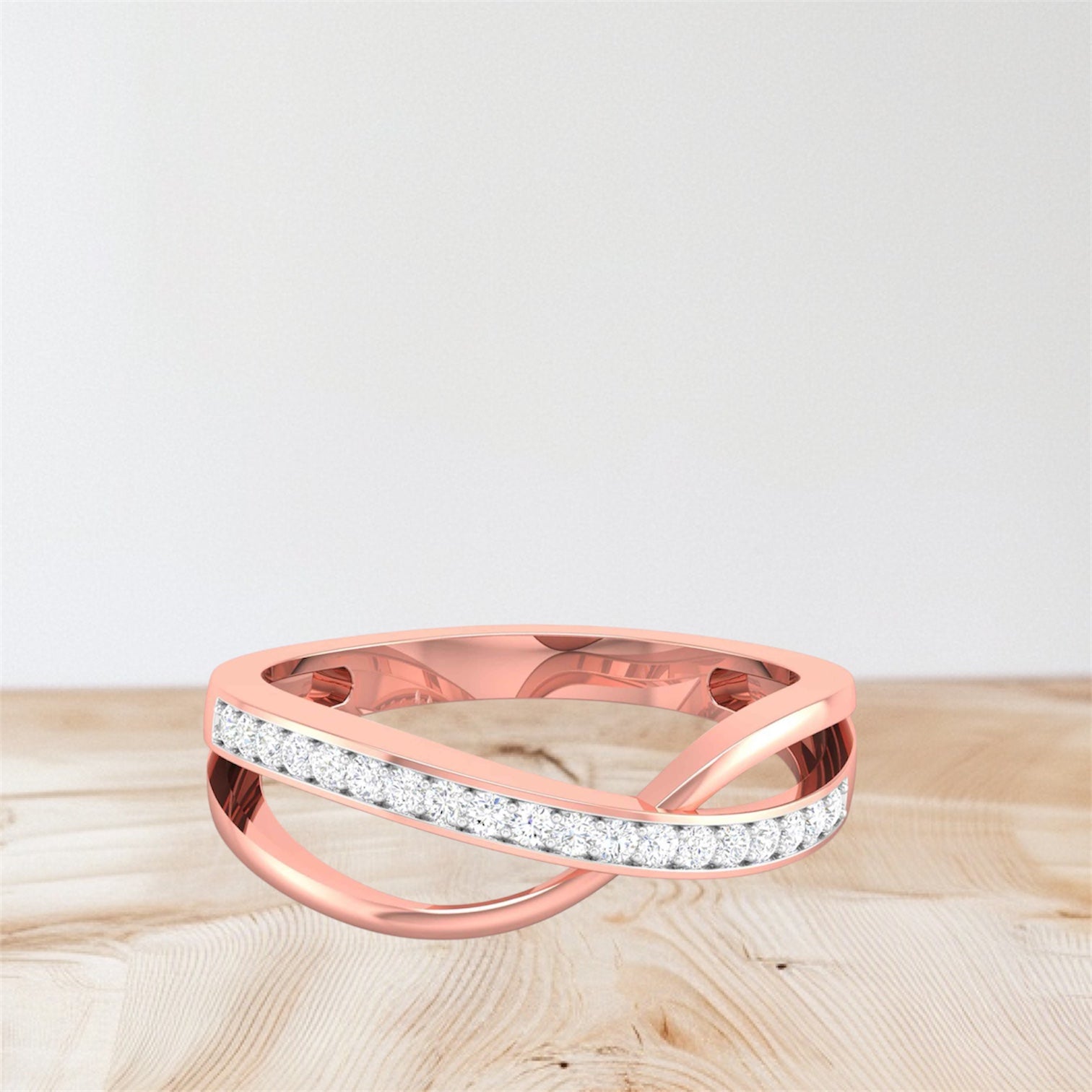 Rose gold ring with diamond accents on a light wooden surface
