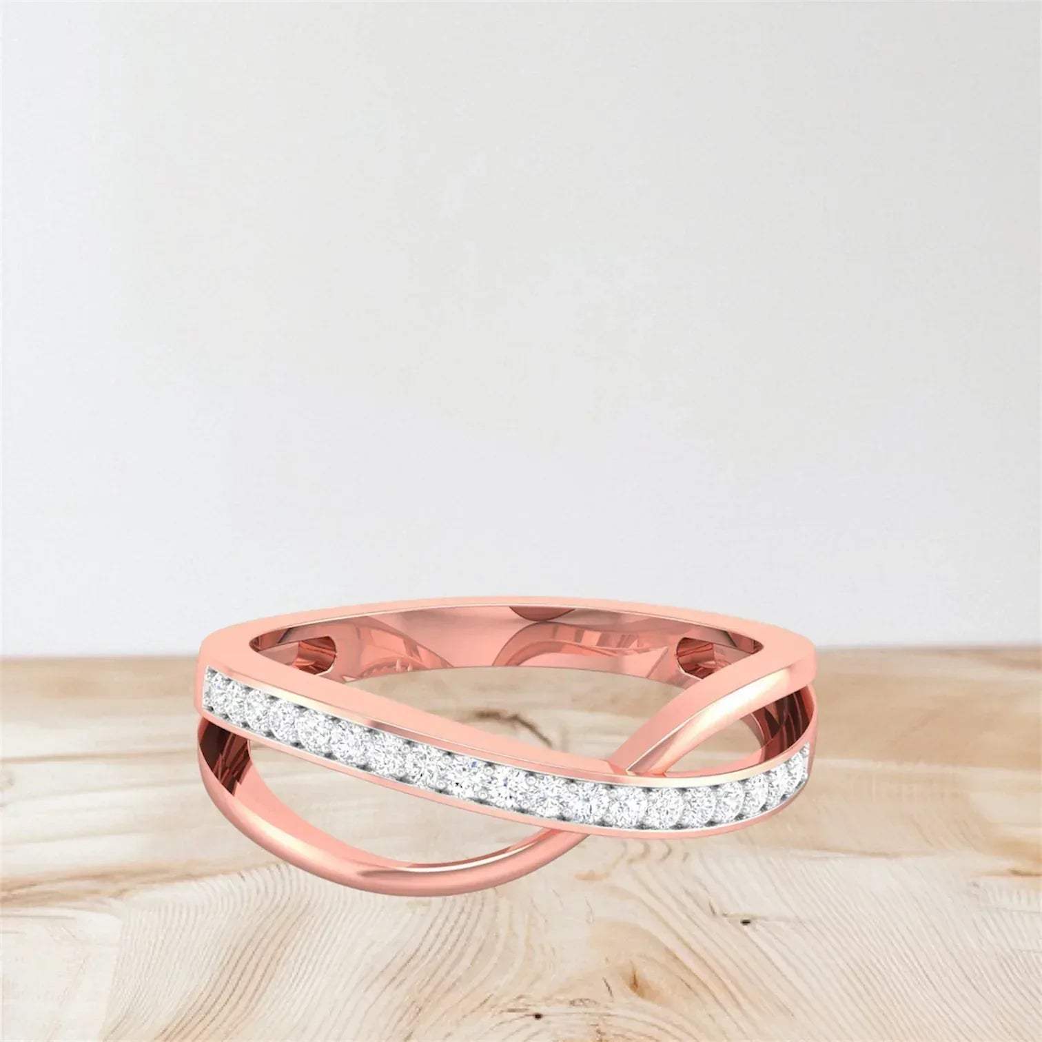 Rose gold ring with diamond accents on a light wooden surface