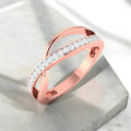 Rose gold ring with diamond accents on a light gray surface