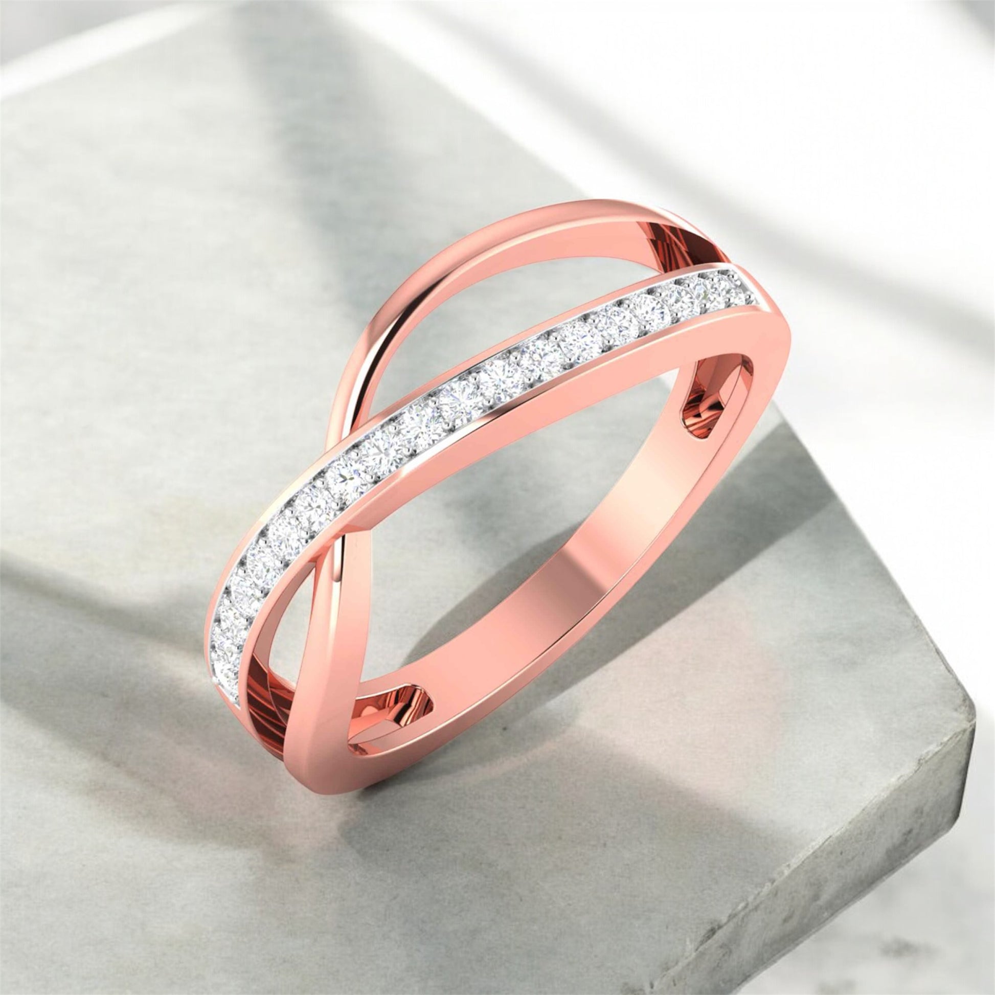 Rose gold ring with diamond accents on a light gray surface
