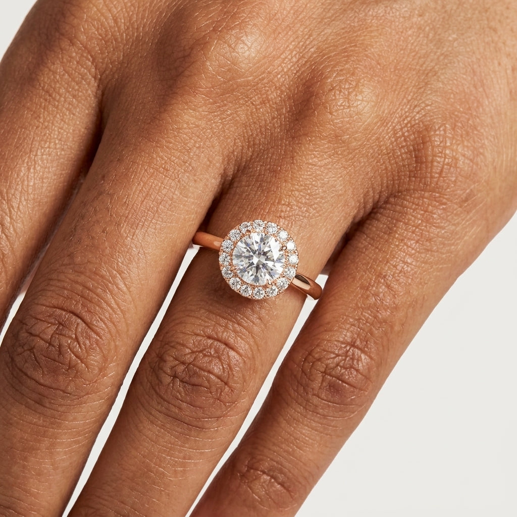 gold ring with solitaire diamond and halo diamond around it on a person's finger