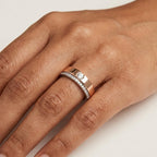 Two tone rose gold and white gold diamond ring on a person's hand that is placed on a white surface