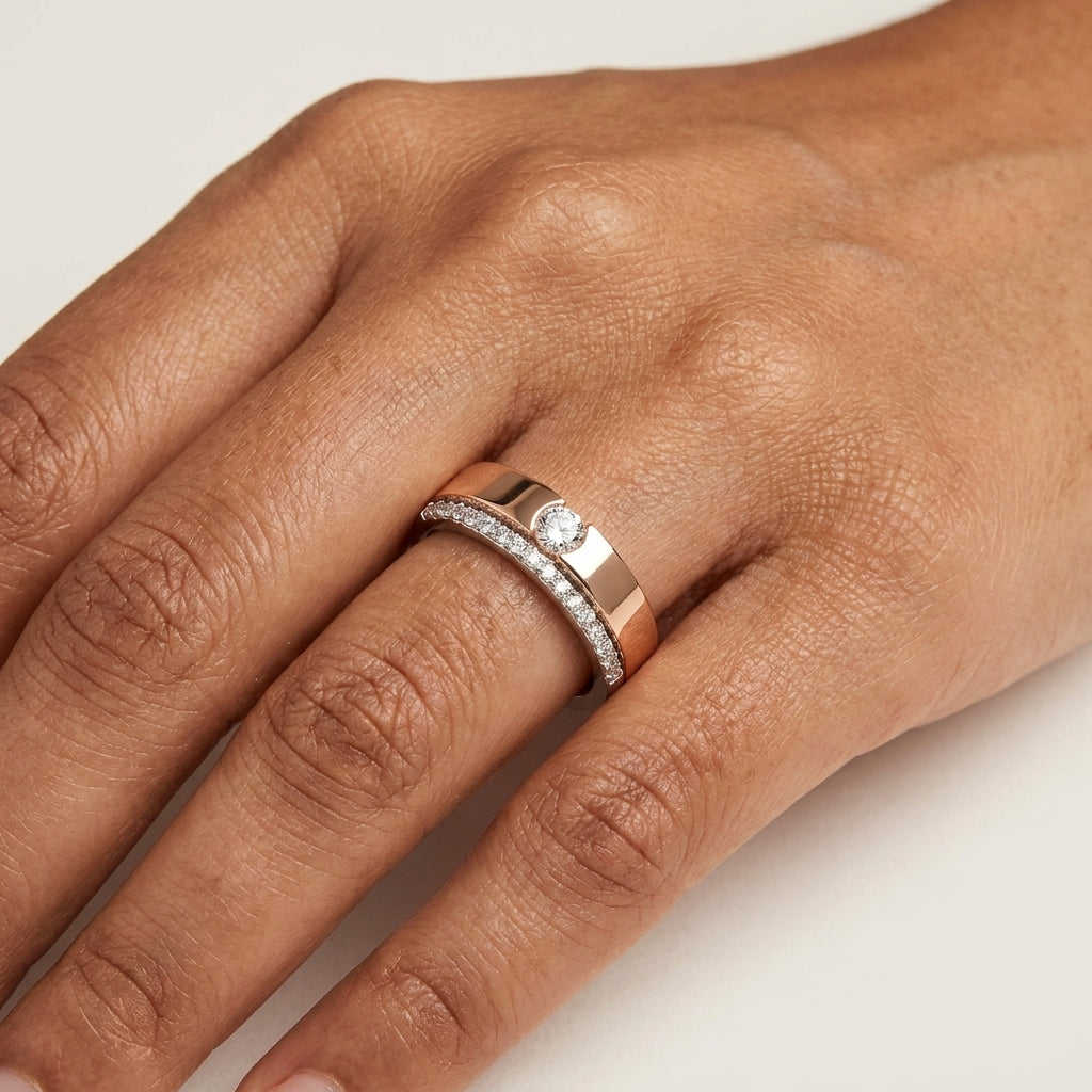 Two tone rose gold and white gold diamond ring on a person's hand that is placed on a white surface