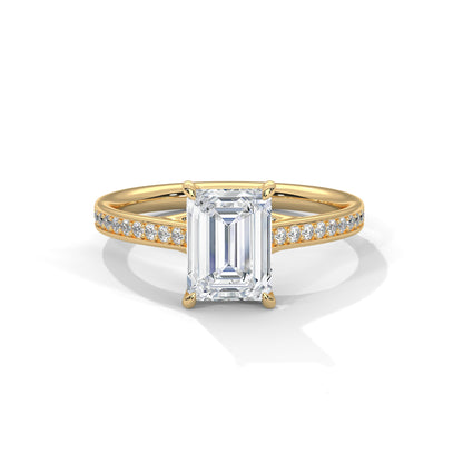 Gold ring with a large emerald-cut diamond and smaller diamonds on the band against a white background.