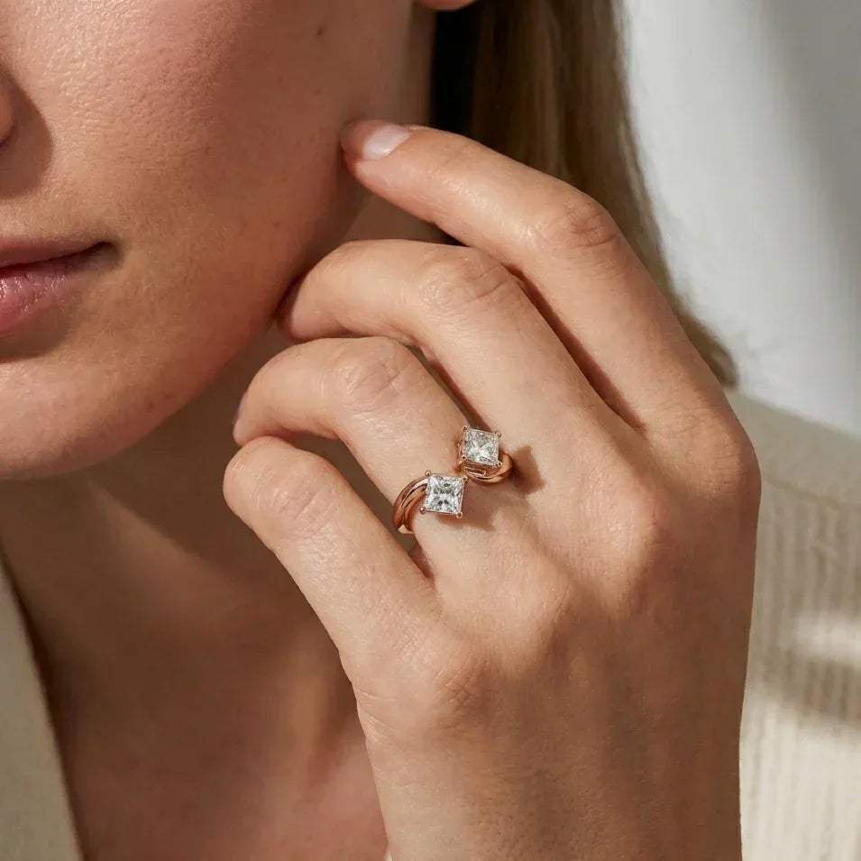 Close-up of a woman's hand wearing two diamonds ring on a neutral background