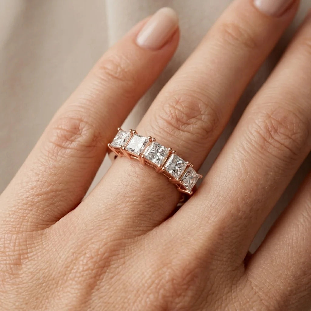 Rose gold diamond ring worn in a hand's finger against a natural background.
