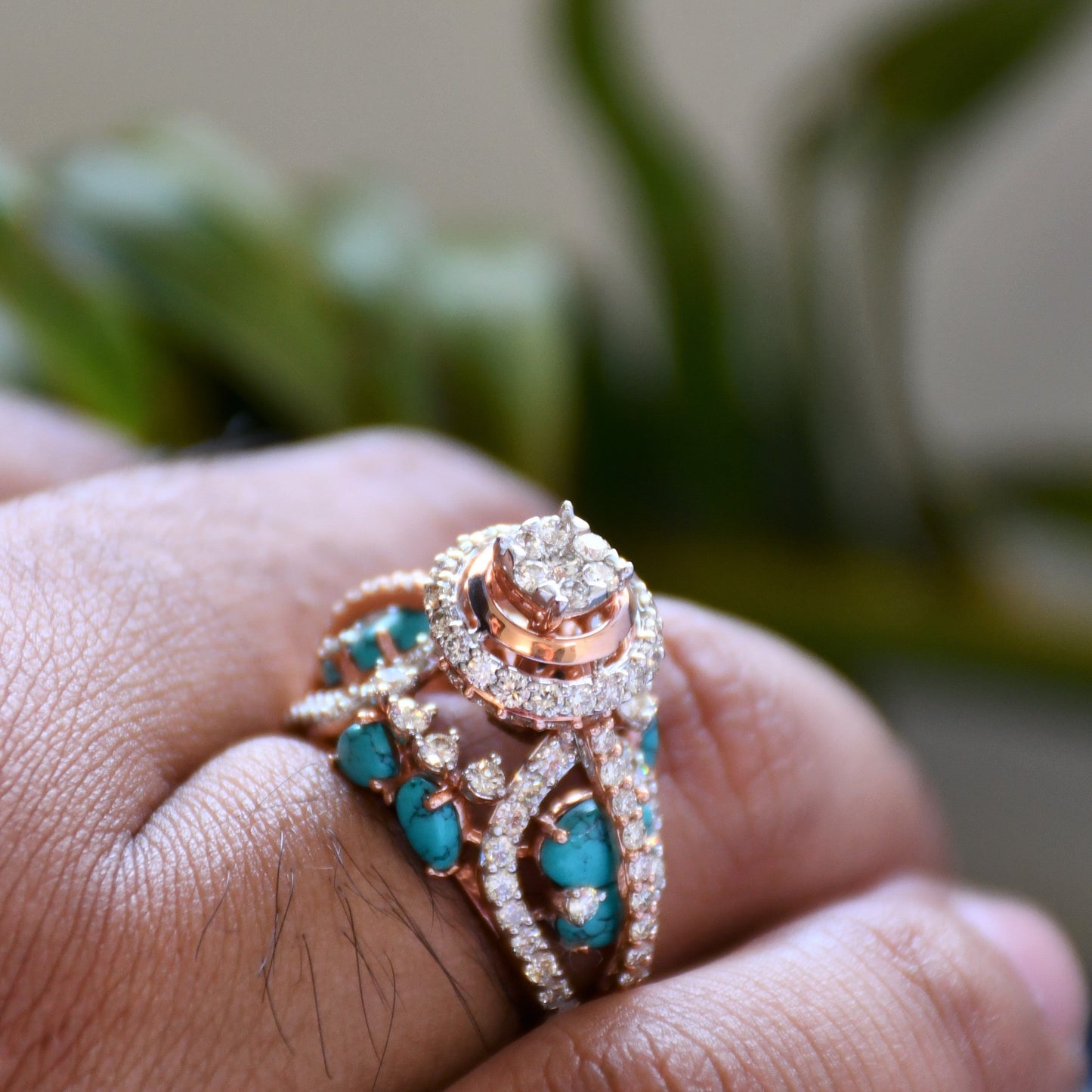 A woman's hand on a rock stone displaying a rose gold diamond ring with a central brilliant cut diamonds and smaller color stones around it.
