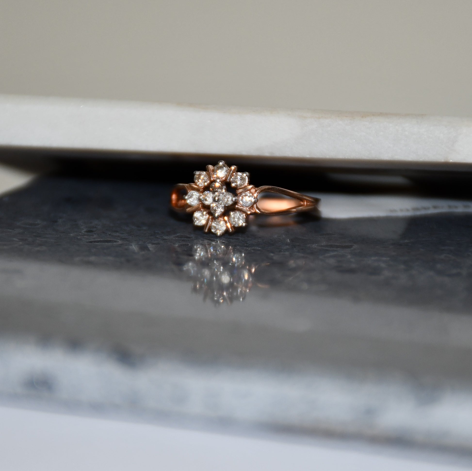 A 14kt gold band ring with a round brilliant cut diamond centerpiece, set on a reflective surface.