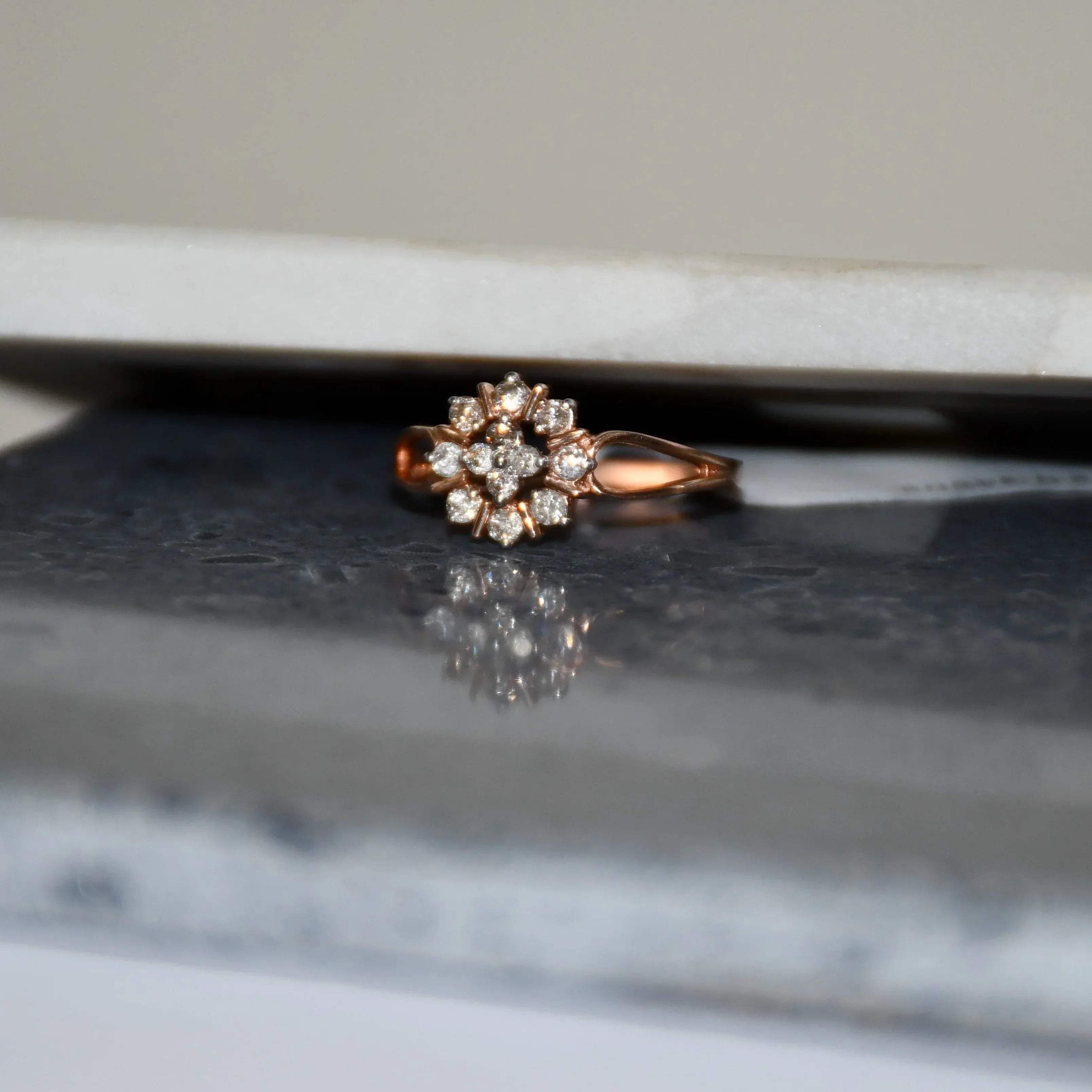 A 14kt gold band ring with a round brilliant cut diamond centerpiece, set on a reflective surface.