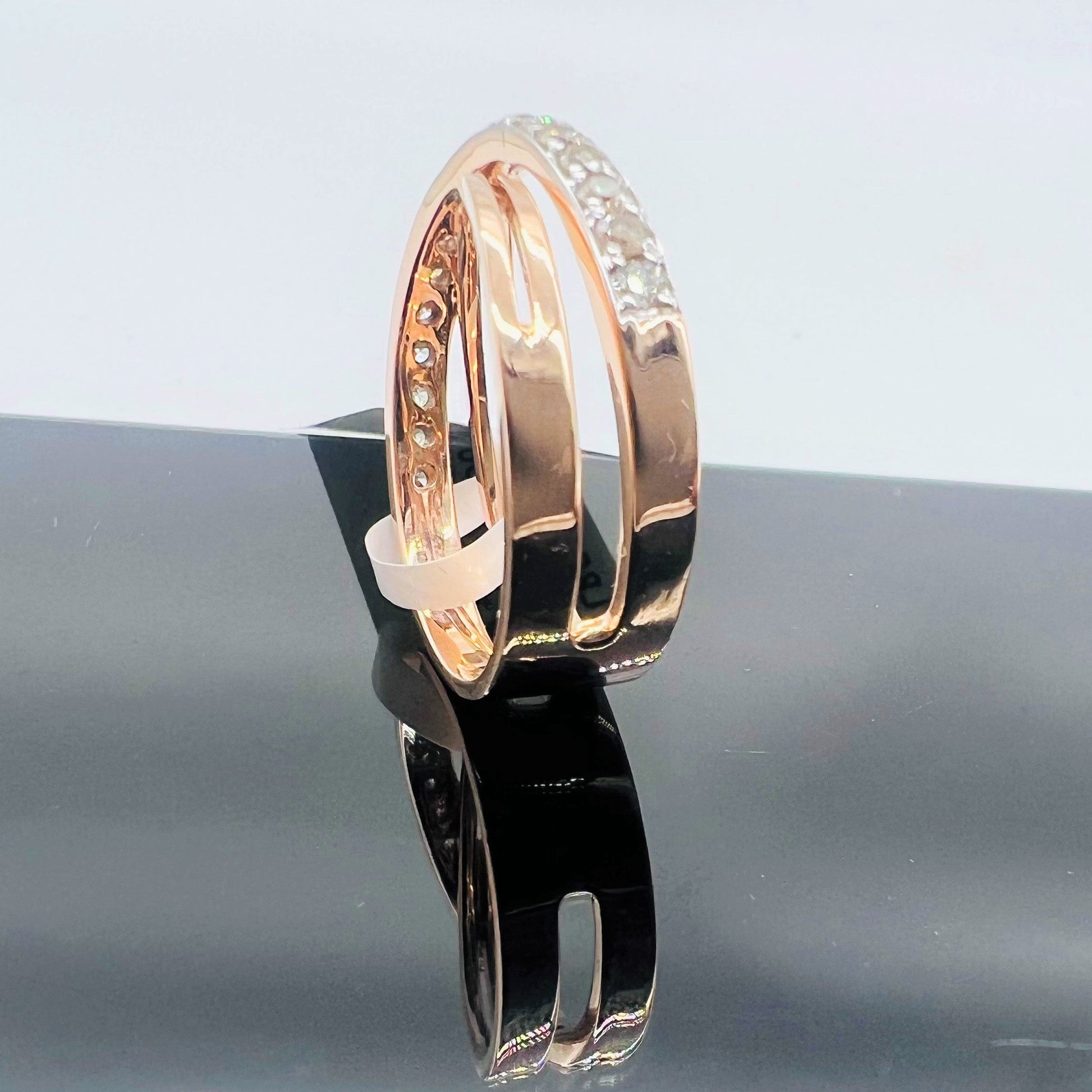 A diamond band ring with 14K gold hallmark, displayed on black reflective surface.