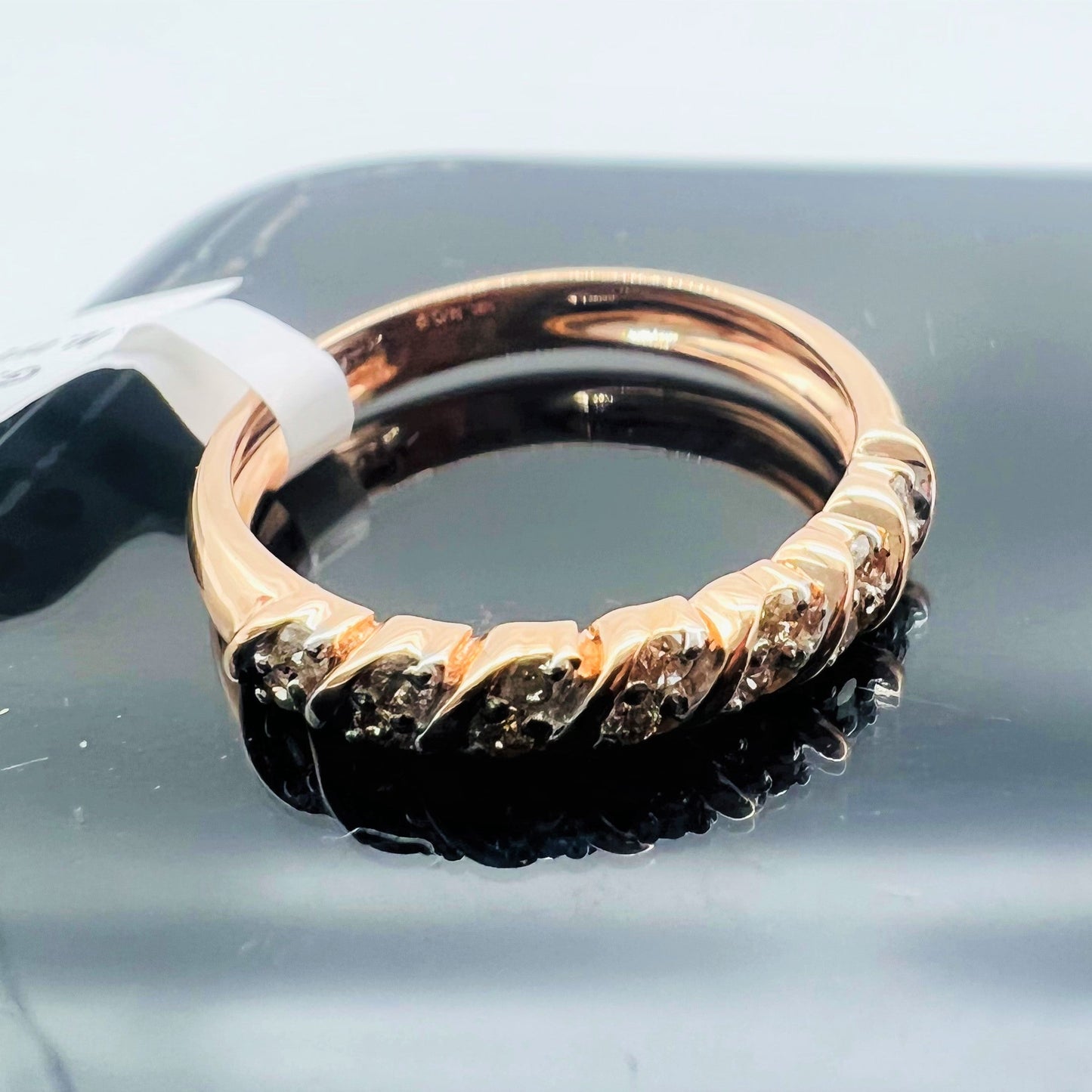 A 14K gold hallmark ring with certified diamonds set around its circumference is displayed on a reflective surface.