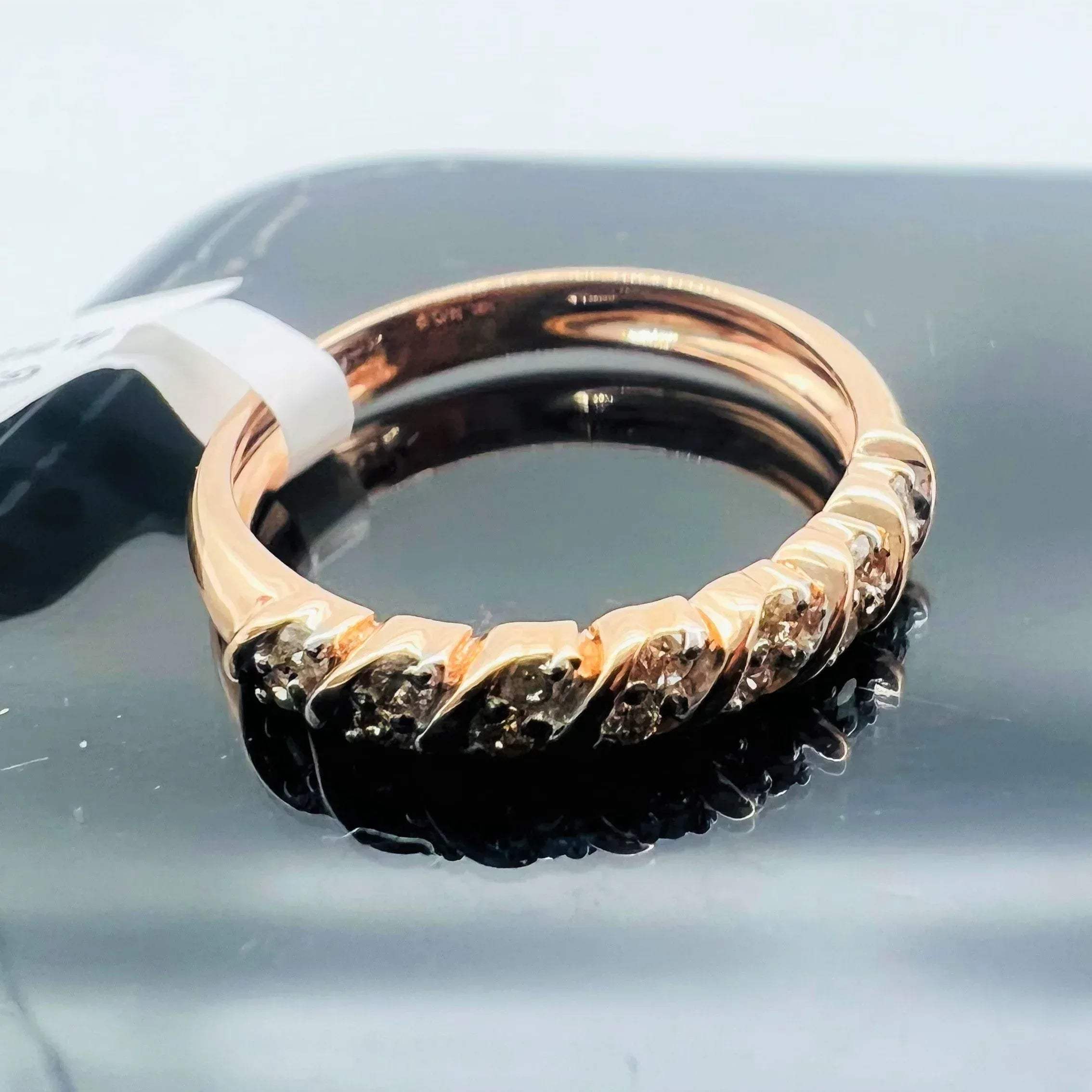 A 14K gold hallmark ring with certified diamonds set around its circumference is displayed on a reflective surface.
