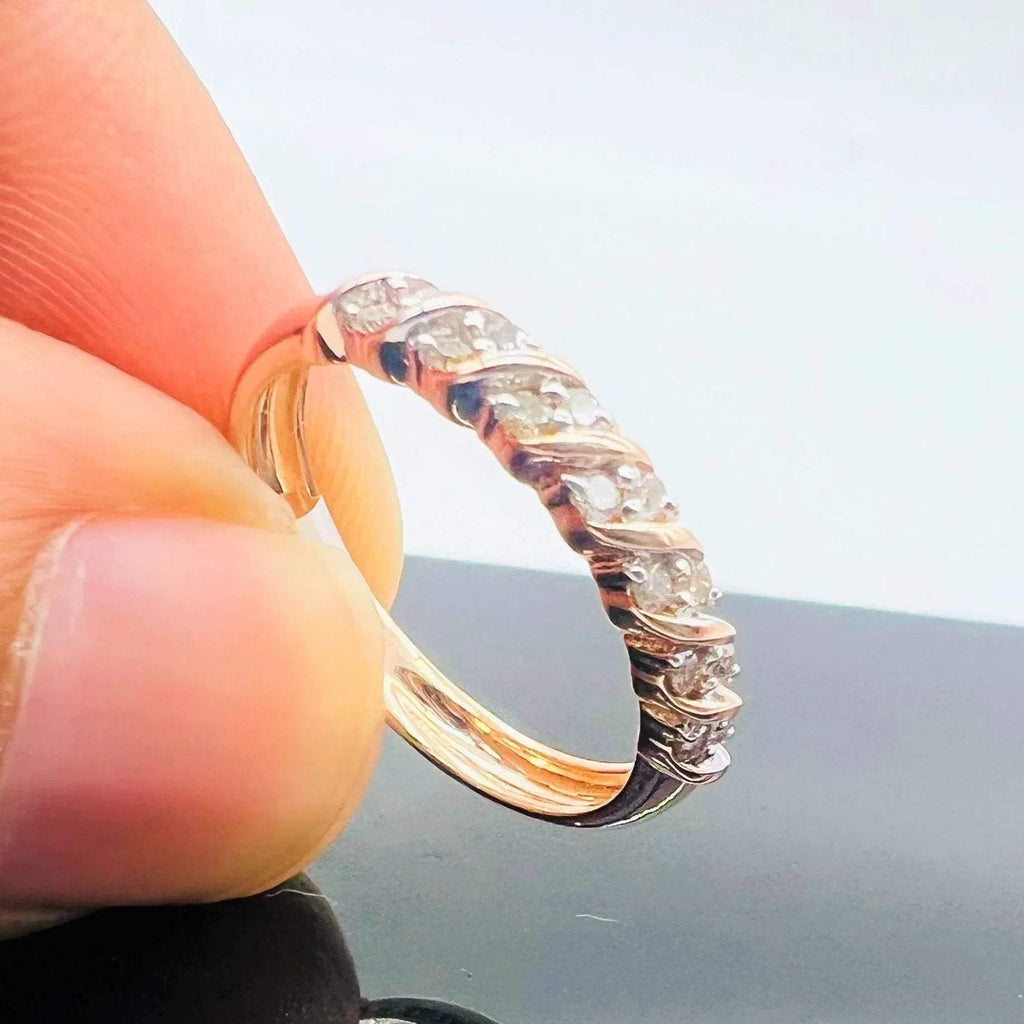 A person's hand holding a 14K gold hallmark ring with certified diamonds set around its circumference.