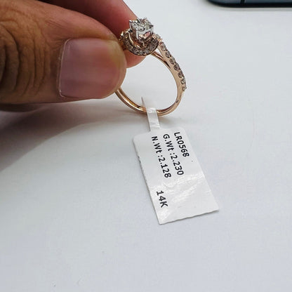 A 14kt gold hallmarked diamond band ring with a brilliant cut diamond centerpiece, held between fingers.