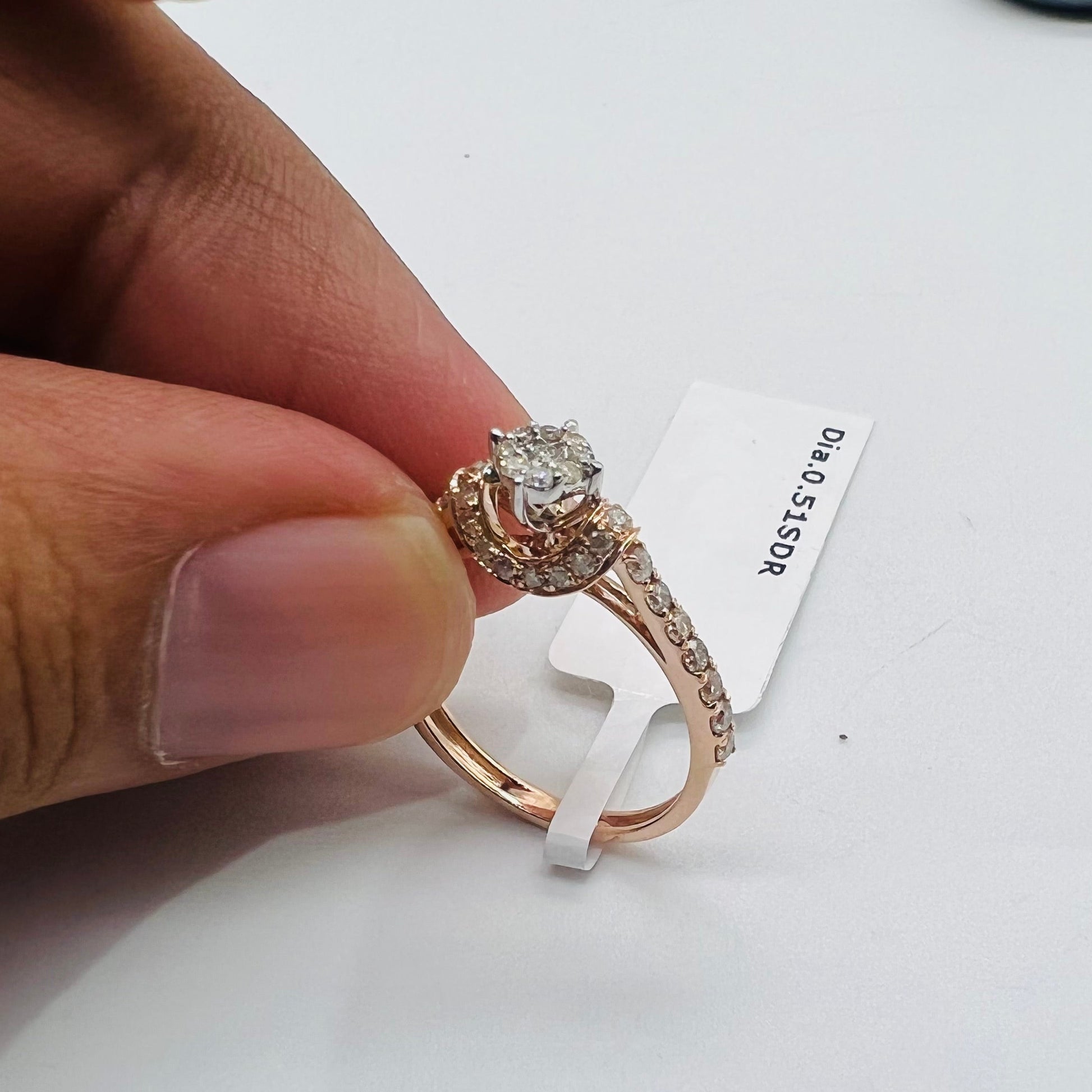 A 14kt gold hallmarked diamond band ring with a brilliant cut diamond centerpiece, held between fingers.