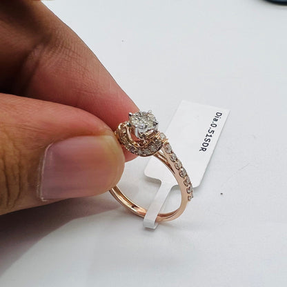 A 14kt gold hallmarked diamond band ring with a brilliant cut diamond centerpiece, held between fingers.