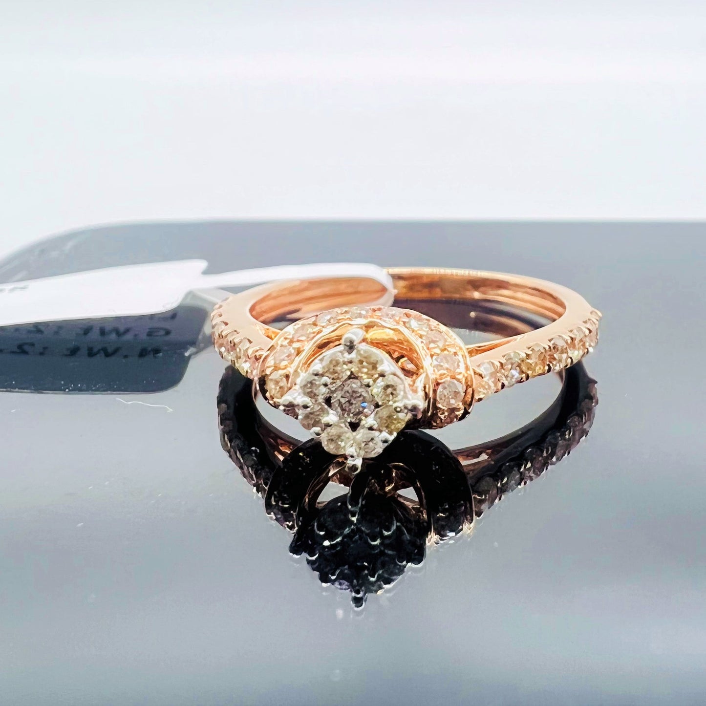 A 14kt gold hallmarked diamond band ring with a brilliant cut diamond centerpiece, displayed on a reflective surface.