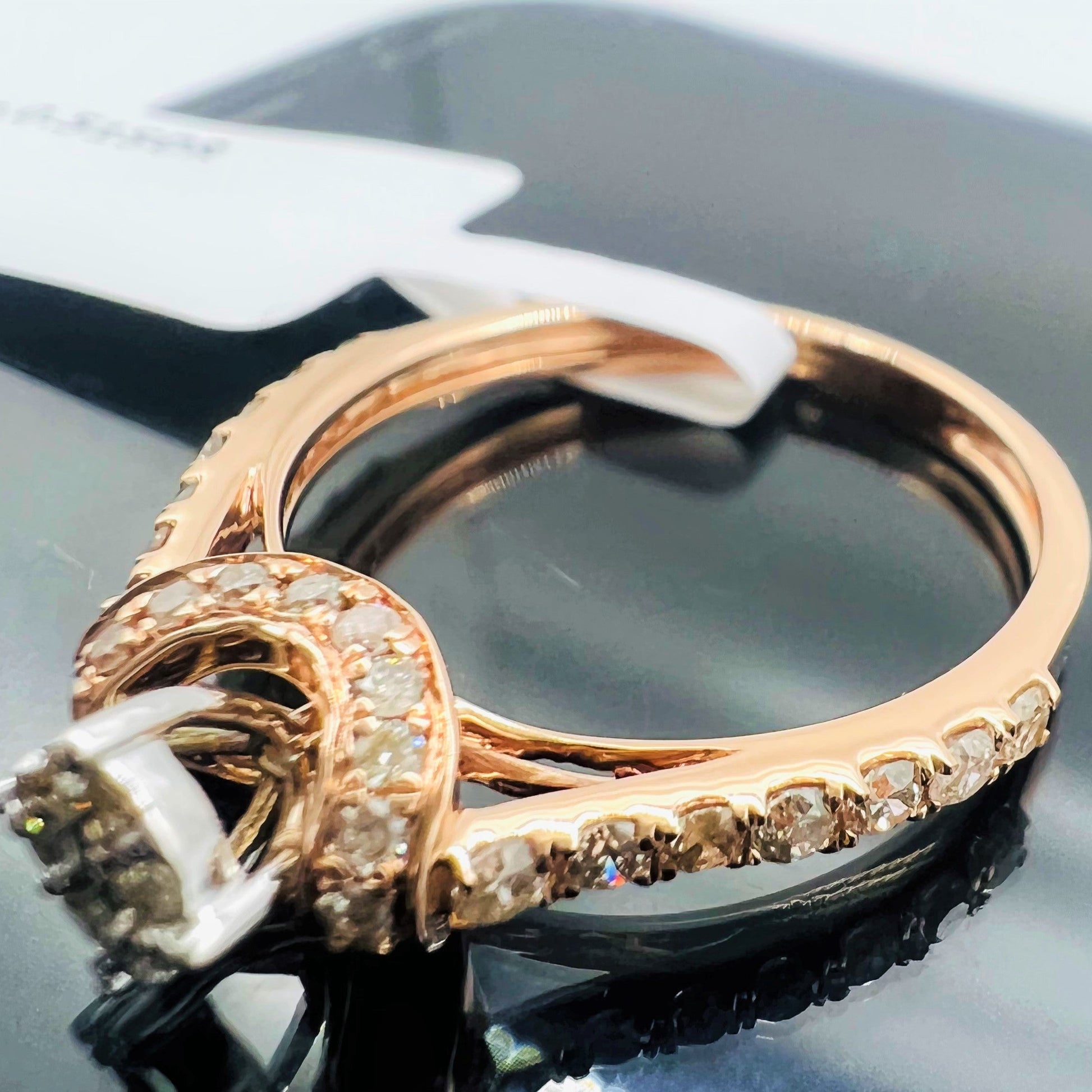 A 14kt gold hallmarked diamond band ring with a brilliant cut diamond centerpiece, displayed on a reflective surface.