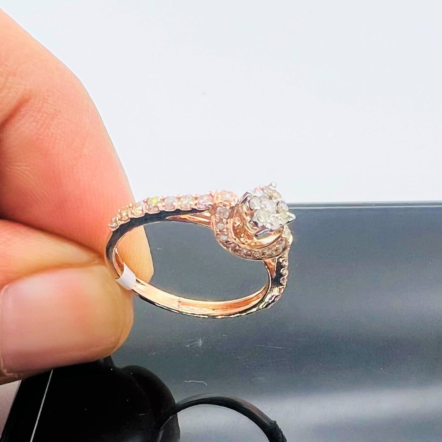 A 14kt gold hallmarked diamond band ring with a brilliant cut diamond centerpiece, held between fingers.