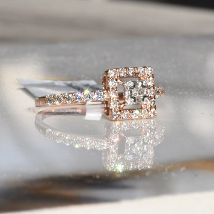 A 14K gold ring with a central square-shaped setting holding a sparkling, multicolored diamond, surrounded by smaller round diamonds set in a polished, reflective surface.