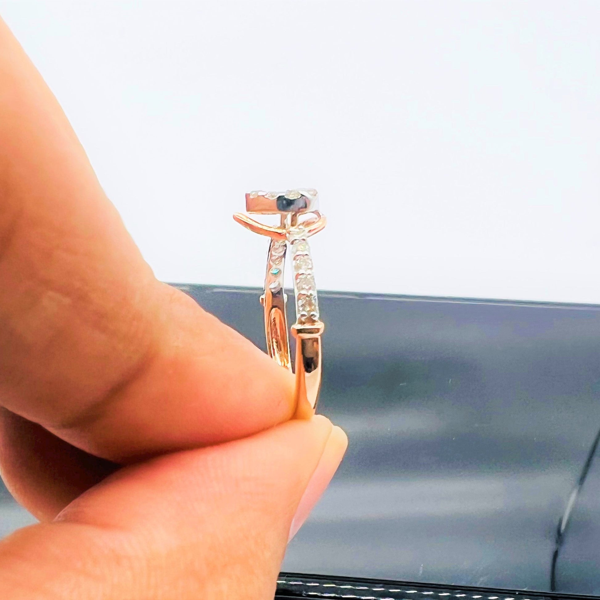 Hand holding a gold ring with a pear-shaped diamond center stone and a band adorned with small round diamonds.