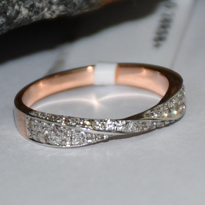Elegant two-tone diamond ring featuring intertwined bands of rose gold and white gold, adorned with small round-cut diamonds, displayed on a white paper.