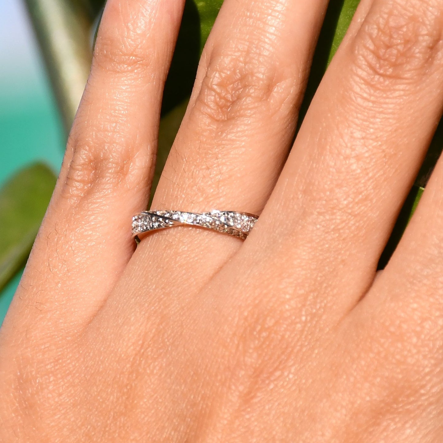 Elegant two-tone diamond ring featuring intertwined bands of rose gold and white gold, adorned with small round-cut diamonds, displayed worn in a hand's finger.