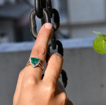 A person's hand displaying a green semi-precious stone ring with a 14KT gold band and brilliant cut diamonds on the top and bottom.