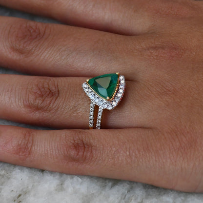 A person's hand displaying a green semi-precious stone ring with a 14KT gold band and brilliant cut diamonds on the top and bottom.