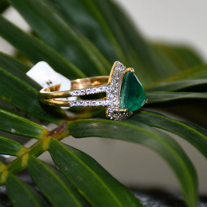 A green semi-precious stone ring with a 14KT gold band and brilliant cut diamonds on the top and bottom is displayed on a green leaf.