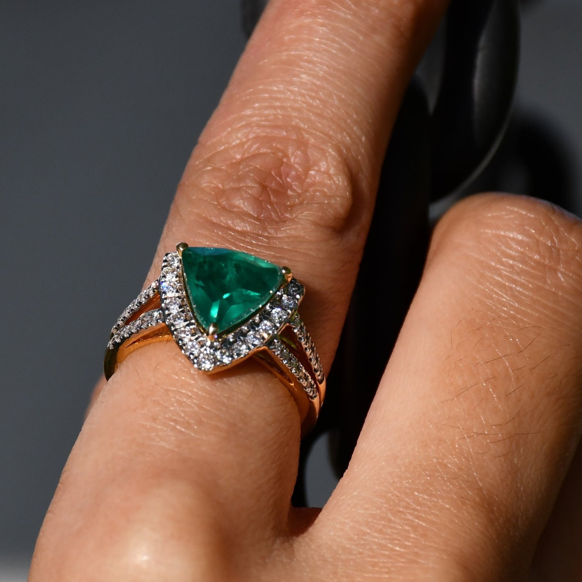 A person's hand displaying a green semi-precious stone ring with a 14KT gold band and brilliant cut diamonds on the top and bottom.