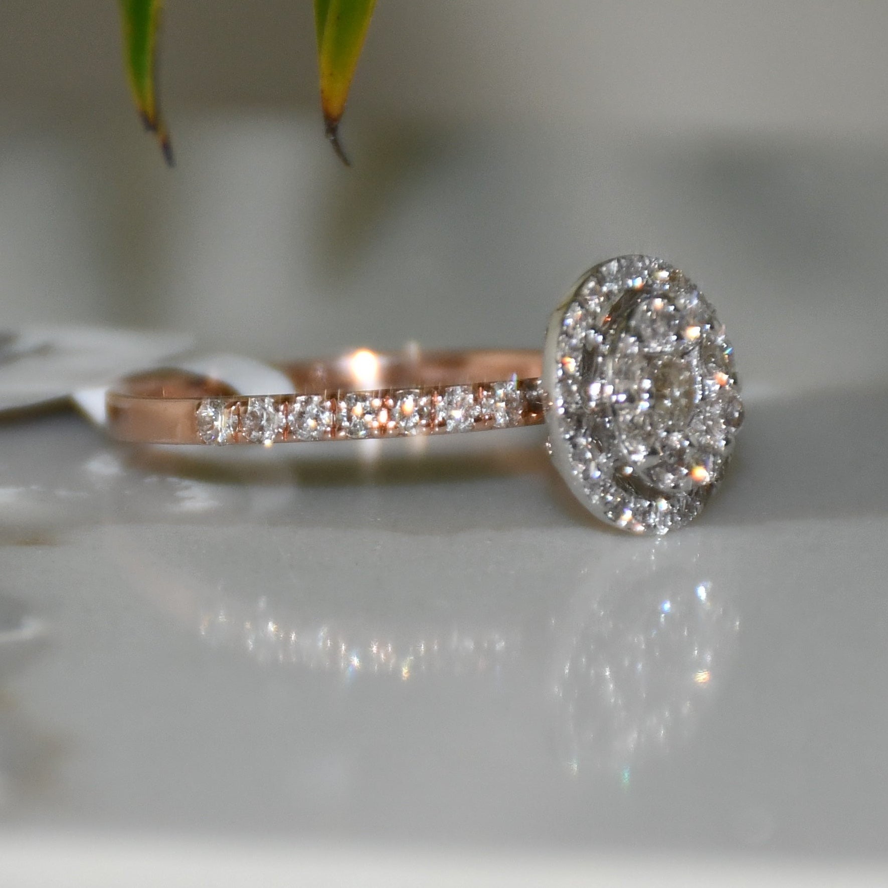 A diamond ring is displayed on a reflective surface.