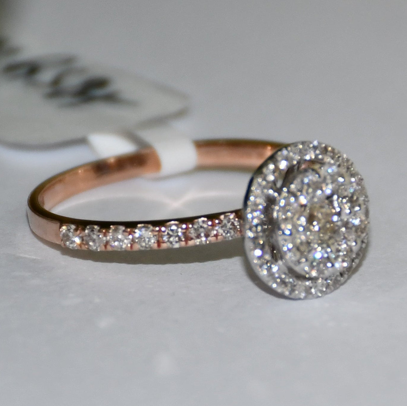 A diamond ring is displayed on a smooth white surface.