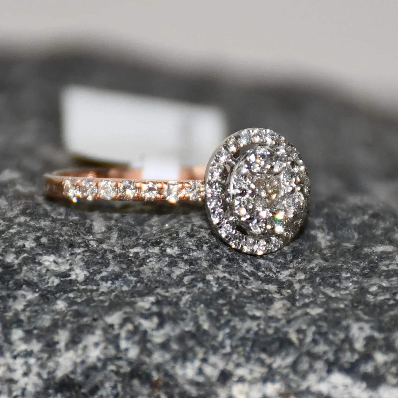 A diamond ring is displayed on a rough and textured surface.